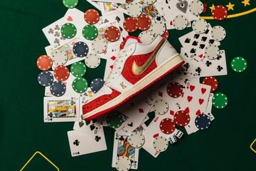 Hier liegt der Jordan 1 Low Spades auf einem grünen Tisch mit vielen Pokerspielkarten und Pokerchips
