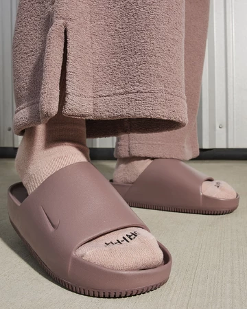 Ein Model trägt die Nike Calm Slide Smokey Mauve