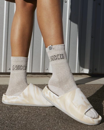 Ein Model trägt die Nike Calm Slide Phantom am Fuß