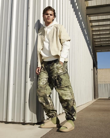 Ein Model trägt die Nike Calm Slide Khaki am Fuß