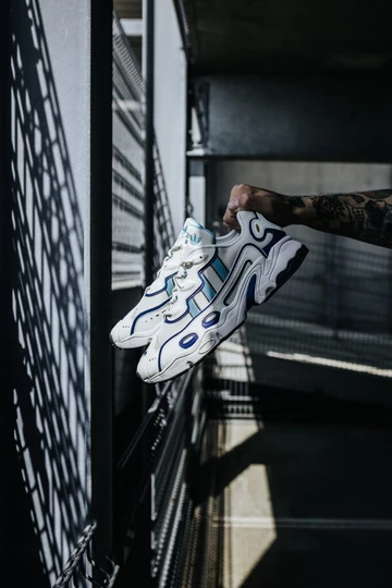 adidas Ozweego OG Royal Blue Schuh wird von der Sonne durch Gitter angestrahlt 2