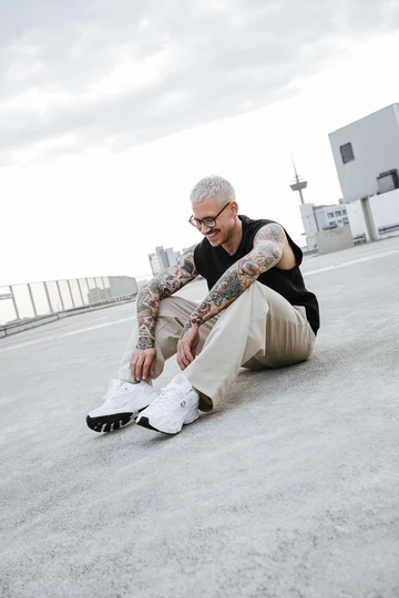 adidas Astir Cloud White Christopher's gesamtes Outfit. Er sitzt lachend auf dem Boden