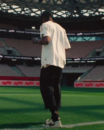 Travis Scott in a Stadium with the Jordan Cut The Check on Feet form behind