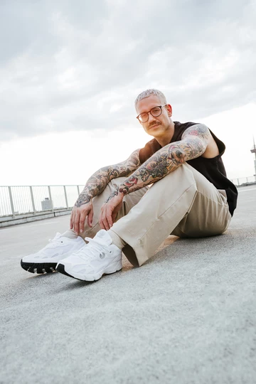 adidas Astir Cloud White Christopher's gesamtes Outfit. Er sitzt auf dem Boden.