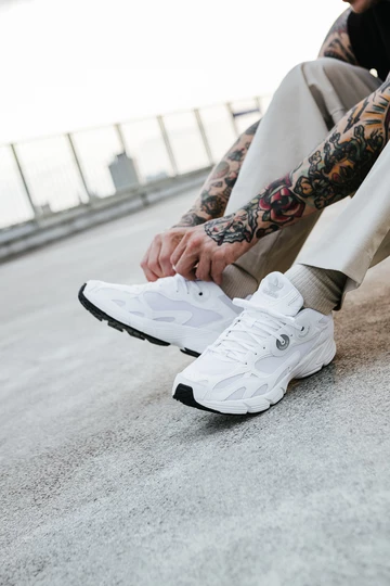 adidas Astir Cloud White am Fuß. Christopher bindet die Schnürsenkel