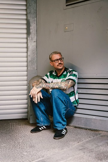 adidas Handball Spezial Core Black Christopher sitzt vor einer Garage