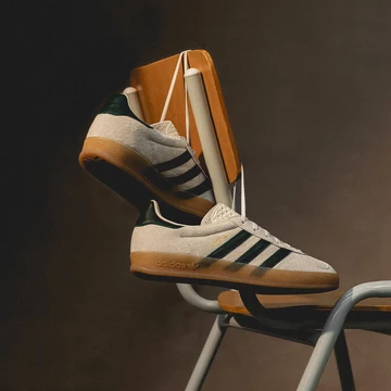 Die adidas Gazelle Indoor Cream White abgelichtet von Asphaltgold, sie hängt an einem Stuhl