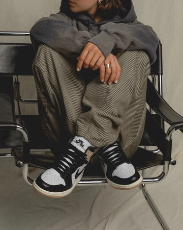 Jordan 1 High Latte Lookbook Model sitzt auf einem Stuhl