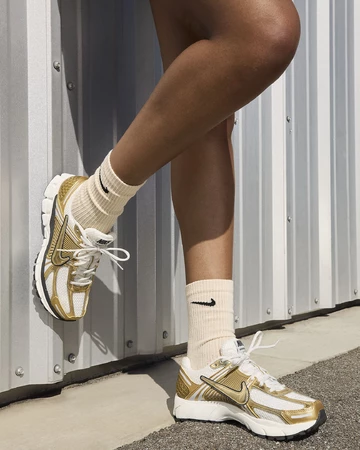 Ein Model trägt den Nike Zoom Vomero 5 Gold am Fuß