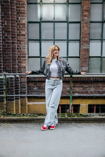 Clara steht an einer Backsteinwand und trägt den adidas Campus 00s Scarlet Red