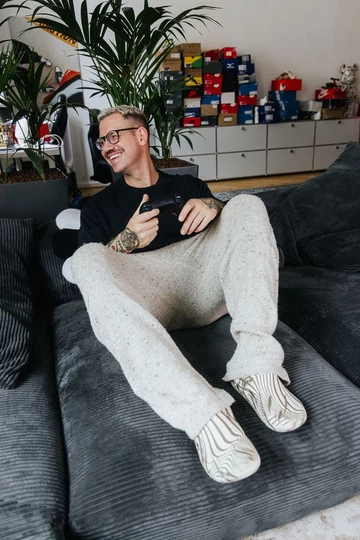 Christopher sitzt auf der Couch und dabei trägt er den Palace x Crocs Bone