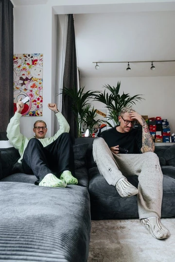Palace x Crocs Mellow Clog - Christopher sitzt in zwei verschiedenen Outfits auf seiner Couch, es sieht aus als hätte er einen Zwillingsbruder.