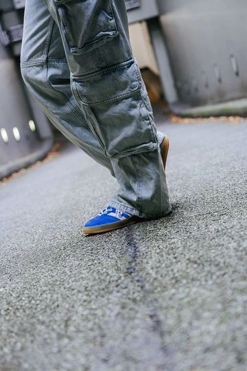 Clara sitzt auf dem Bordstein und trägt die adidas Gazelle Indoor Blue