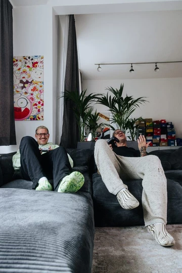 Palace x Crocs Mellow Clog - Christopher sitzt in zwei verschiedenen Outfits auf seiner Couch, es sieht aus als hätte er einen Zwillingsbruder.