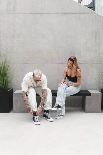 Clara und Christopher sitzen auf einer Bank und tragen den Converse Chuck 70's