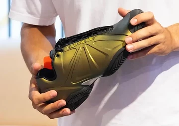 Supreme x Nike Air Zoom Courtposite Alcatraz hält den Metallic Colourway in der Hand in Detailansicht