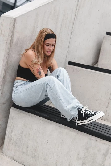 Clara sitzt auf einer Treppe und trägt den Converse Chuck 70's