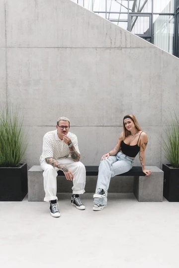 Clara und Christopher sitzen auf einer Bank und tragen den Converse Chuck 70's