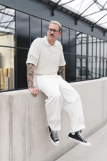 Christopher sitzt auf einer Mauer und trägt den Converse Chuck 70's