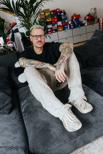 Christopher sitzt auf der Couch und dabei trägt er den Palace x Crocs Bone
