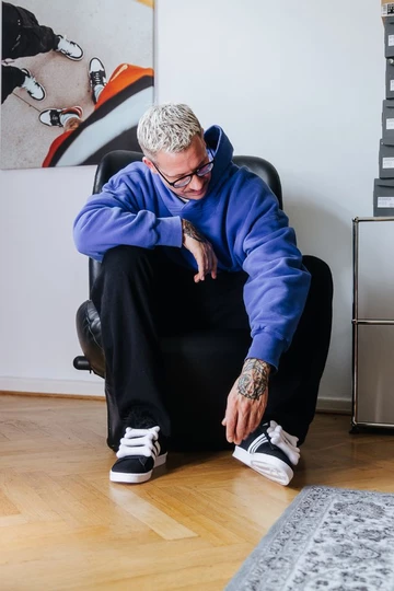 Christopher trägt den Jeremy Scott adidas Campus und sitzt auf einem Sessel