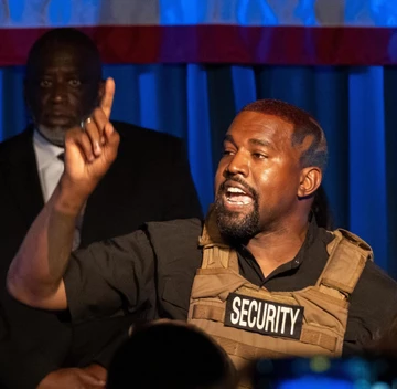 Kanye West disktutiert und trägt eine Security Weste