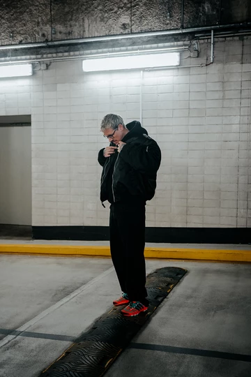 Christopher steht in einem Parkhaus und trägt den adidas adistar Raven im Colorway Solar Orange