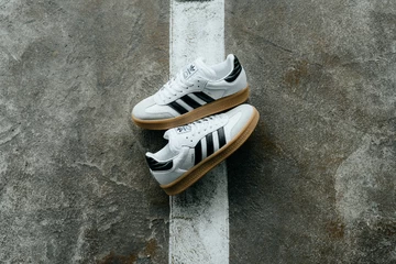 Der adidas Samba XLG Core White liegt zwischen zwei Parkplätzen auf dem Boden