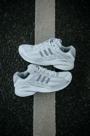 der adidas Adistar Cushion 3 Cloud White liegt zwischen zwei Parkplätzen