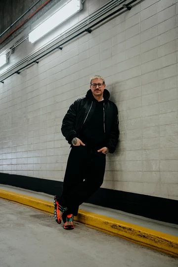 Christopher steht in einem Parkhaus und trägt den adidas adistar Raven im Colorway Solar Orange