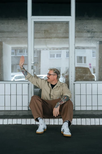 Christopher sitzt und trägt die adidas Gazelle Indoor White Gum am Fuß