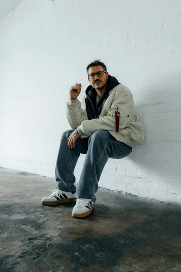 Christohper lehnt an einer Wand und trägt den adidas Samba XLG Core White