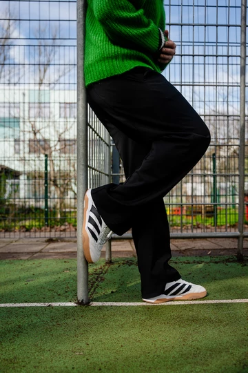 Christopher trägt den adidas Predator Mundial am Fuß, er lehnt an einem Fußballtor