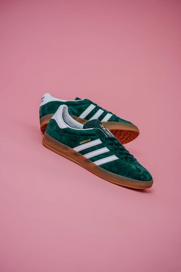 Die adidas Gazelle Indoor Green auf rosafarbenem Rollhintergrund