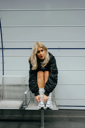 Clara sitzt auf einer Bank und trägt den neuen Nike V2K Run OG am Fuß