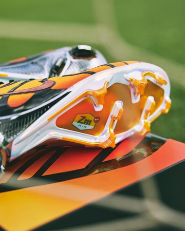 Der Air Max Plus Mercurial Vapor 15 Pimento liegt auf einem Fußballplatz auf seinem Karton