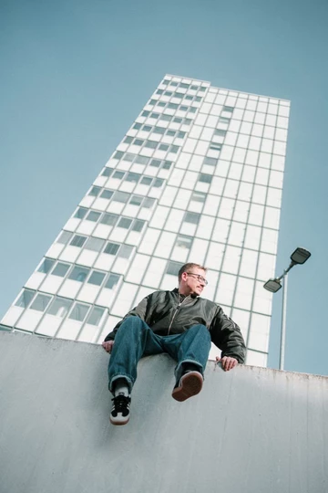 Christopher sitzt auf einer Mauer und trägt den adidas Samba Black Wonder White im Wales Bonner Style