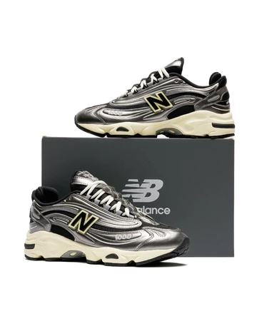 Der New Balance 1000 Metallic Silver steht auf einem Karton