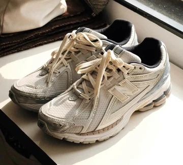 Der Kith New Balance 1906R White Blue steht auf einer Fensterbank in der Sonne