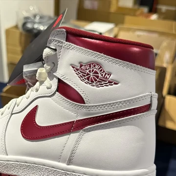 Jemand hält den Jordan 1 High 85 Metallic Burgundy in die Kamera