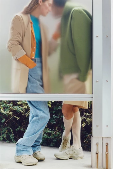 Der AURALEE New Balance WRPD Runner in Bone am Fuß eines Models