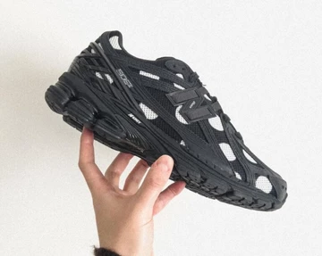 Jemand hält den schwarzen Colorway des New Balance 1906R Polka Dot Pack in der Hand