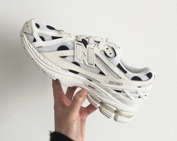 Jemand hält den weißen Colorway des New Balance 1906R Polka Dot Pack in der Hand