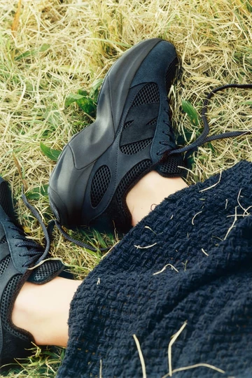 Der AURALEE New Balance WRPD Runner in Phantom am Fuß eines Models